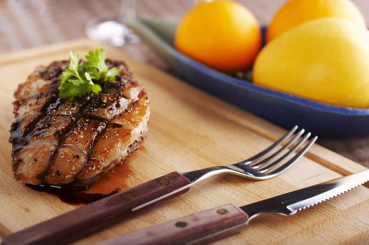 Duck fillet on wood board with fork and knife