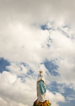Clouds on the sky and Big figure of the Madonna in Lourdes - France.