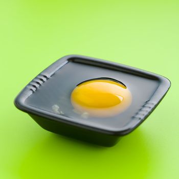 Egg on the black cup over a green table