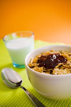 Corn flakes on the vase with jam and spoon