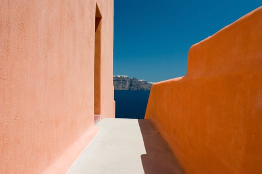 Narrow sidewalk between orange walls and island city afar off