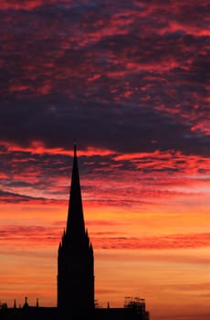 A portrait image of Salisbury cathedral, Wiltshire, with a winter sunset background.