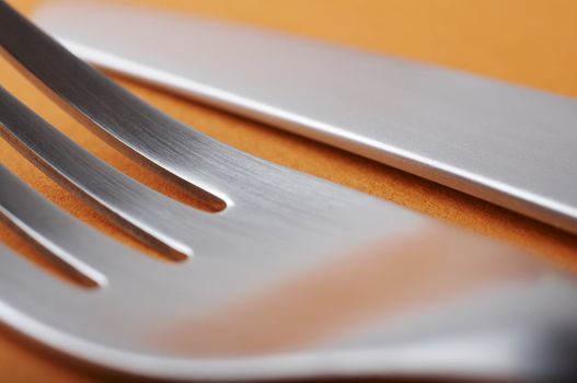 close up of fork and knife on orange background