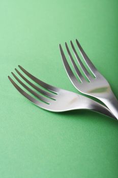 two forks head on green paper background