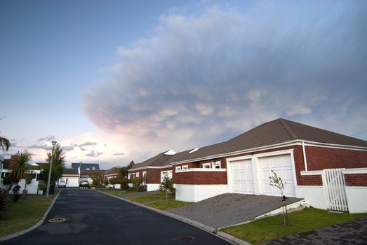 Modern facebrick house with small garden and dramatic clouds overhead