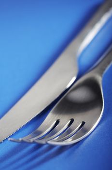 Close up of fork and knife on the blue table