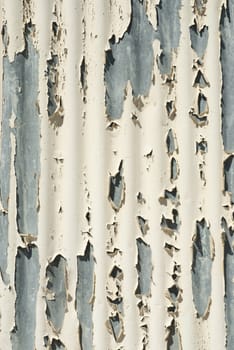 Peeling white paint from curved metal surface on the side of a building