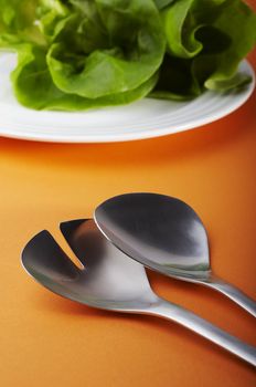Salad spoon and fork on orange background 