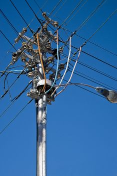 Electricity pole with wires running along it and blue skies in the background
