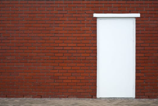 White wooden door in a red brick wall, framed to the right