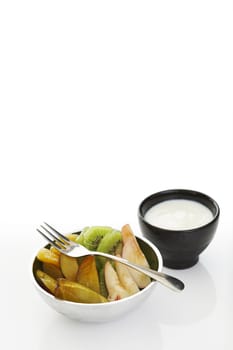 Fruits with yoghurt dip over a white background (lots of copy space)