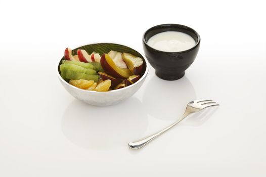 Fruits with yoghurt dip over a white background