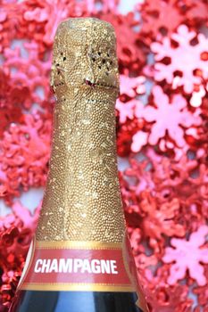 A champagne bottle in close up on a red christmas background