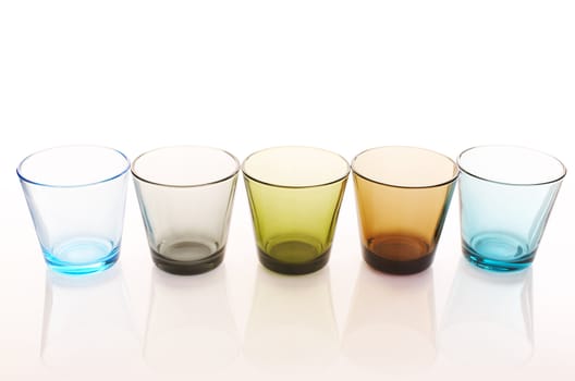 Colorful water glasses over a white reflective background