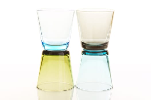 Colorful water glasses stacked over a white reflective background