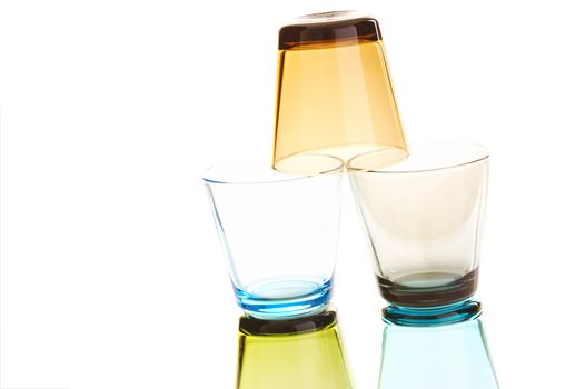 Colorful empty water glasses stacked over a white background