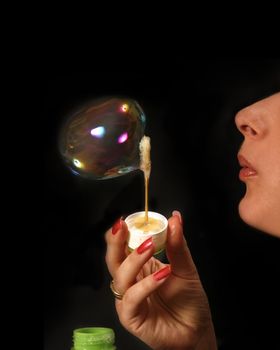 Profile of the woman inflating a soap bubble