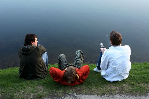 Three young people on a coast of lake