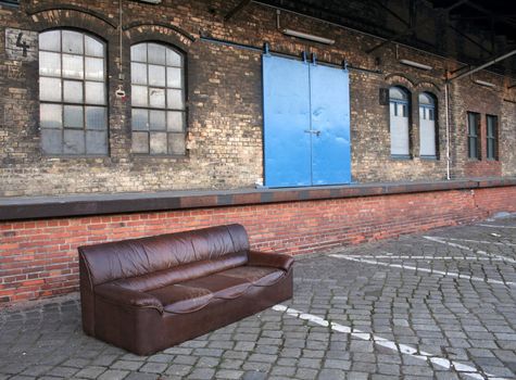 A sofa dumped in an abandoned industrial backyard. Concept shot: recession, unemployment ...