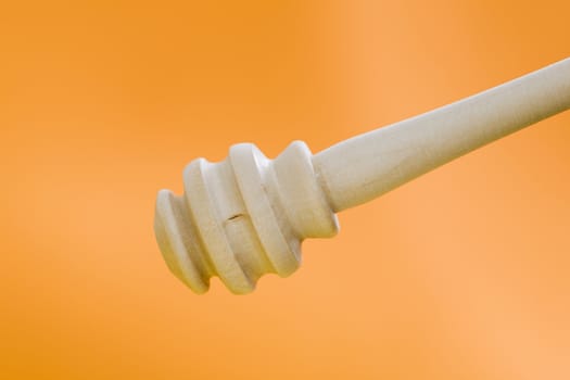 Wooden honey stick over a orange backgound