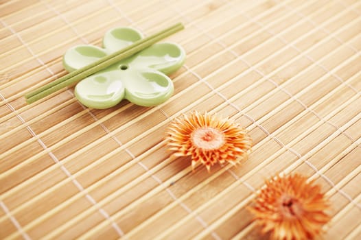 Incense stick on bamboo mat with dried flowers