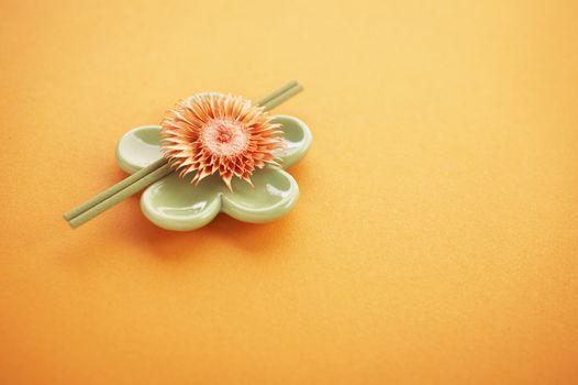 Incense sticks on the orange table with dried flower