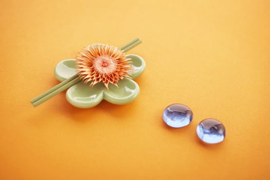 Incense sticks on the orange table with glass stones