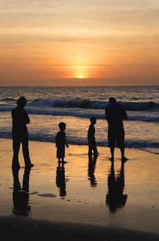 A family at the ocean at sunrise.