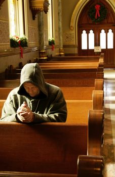 A man praying at a church at Christmas time.