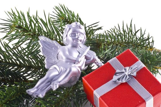 Red giftbox, silver christmas ornaments and part of a christmas tree, on a white background.