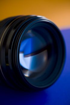 Camera lens close up on blue and orange background