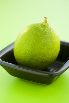 Lime in the small cup over light green background