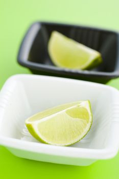 Lime halves in the small cups over light green background