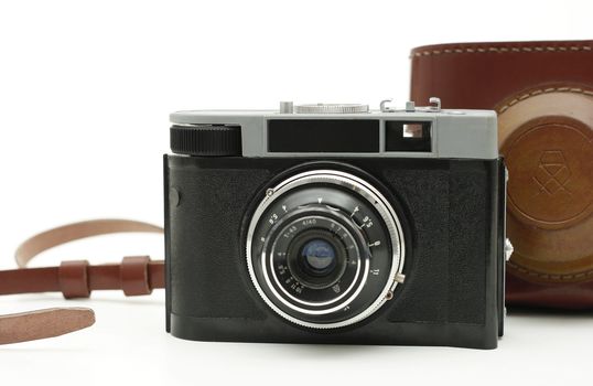 old antique analog photo camera isolated on white with authentic camera bag in background.