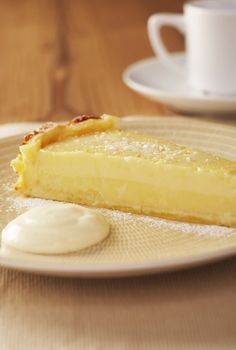 Home made icing sugar topped lime tart with cream on wooden the table