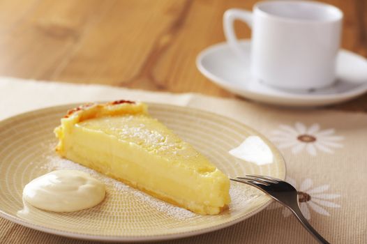 Home made icing sugar topped lime tart with cream on wooden table