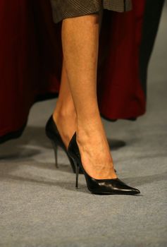 The image of a female leg dressed in black shoes