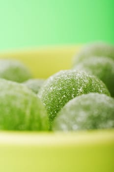 Green marmalade balls in the bowl on the green background