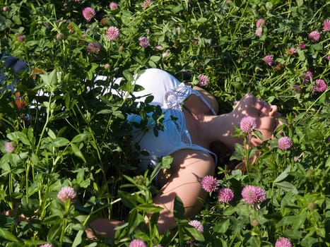 Young beautiful woman girl resting laying between flowers in a field