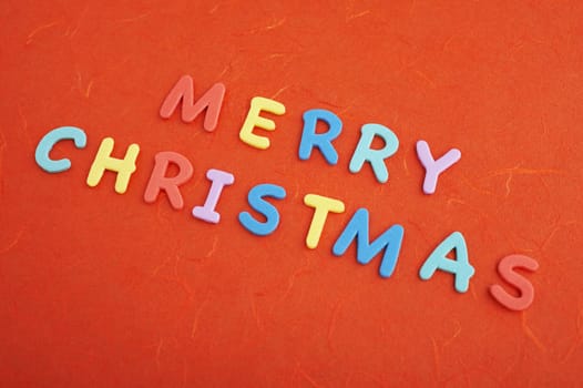 Merry christmas text (colorful soft rubber  letters) on red silk paper