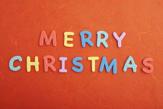 Merry christmas text (colorful soft rubber letters) on red silk paper