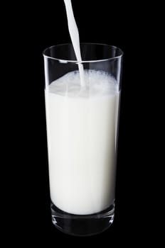 Pouring milk in the glass on black background