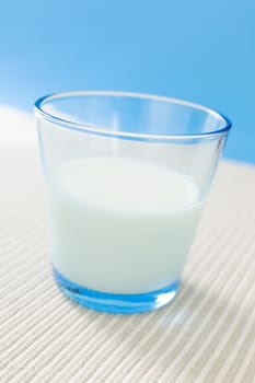 Glass filled with milk over a blue background