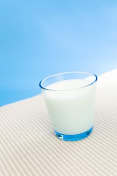Glass filled with milk over a blue background