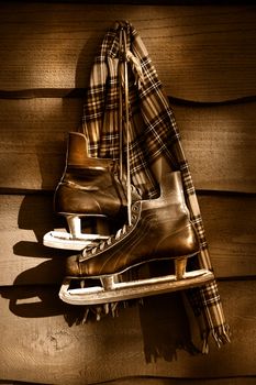 Old hockey skates with scarf hanging on a wall/ Sepia tone filter