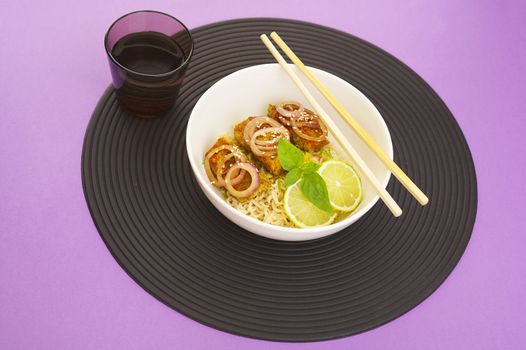 Asian style noodles and deep fried fish on purple background