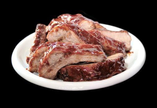 a plate full of juicy barbecued baby back ribs on a black background