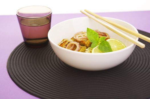Asian style noodles and deep fried fish on purple background