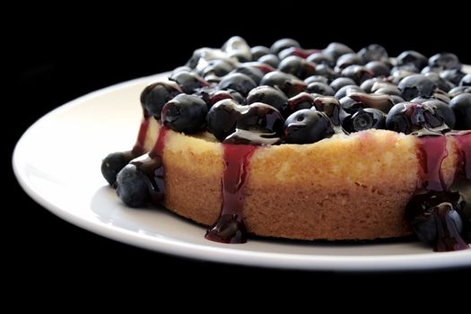 cheesecake topped with glazed blueberries on a black background