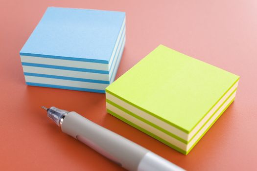 Piles of sticky notes and pen over a pink table